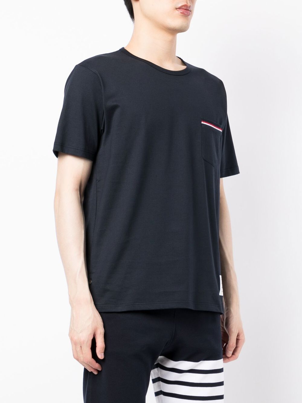 Thom Browne navy jersey pocket tee with RWB stripe trim on chest pocket and collar, featuring woven logo patch at hem