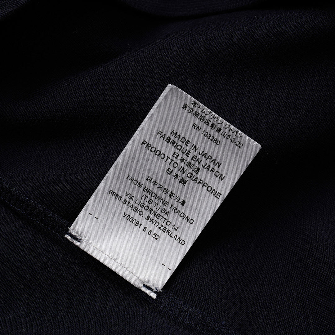 Thom Browne navy short sleeve polo with tonal 4-bar stripe on the sleeve, button placket, and woven brand label at the hem