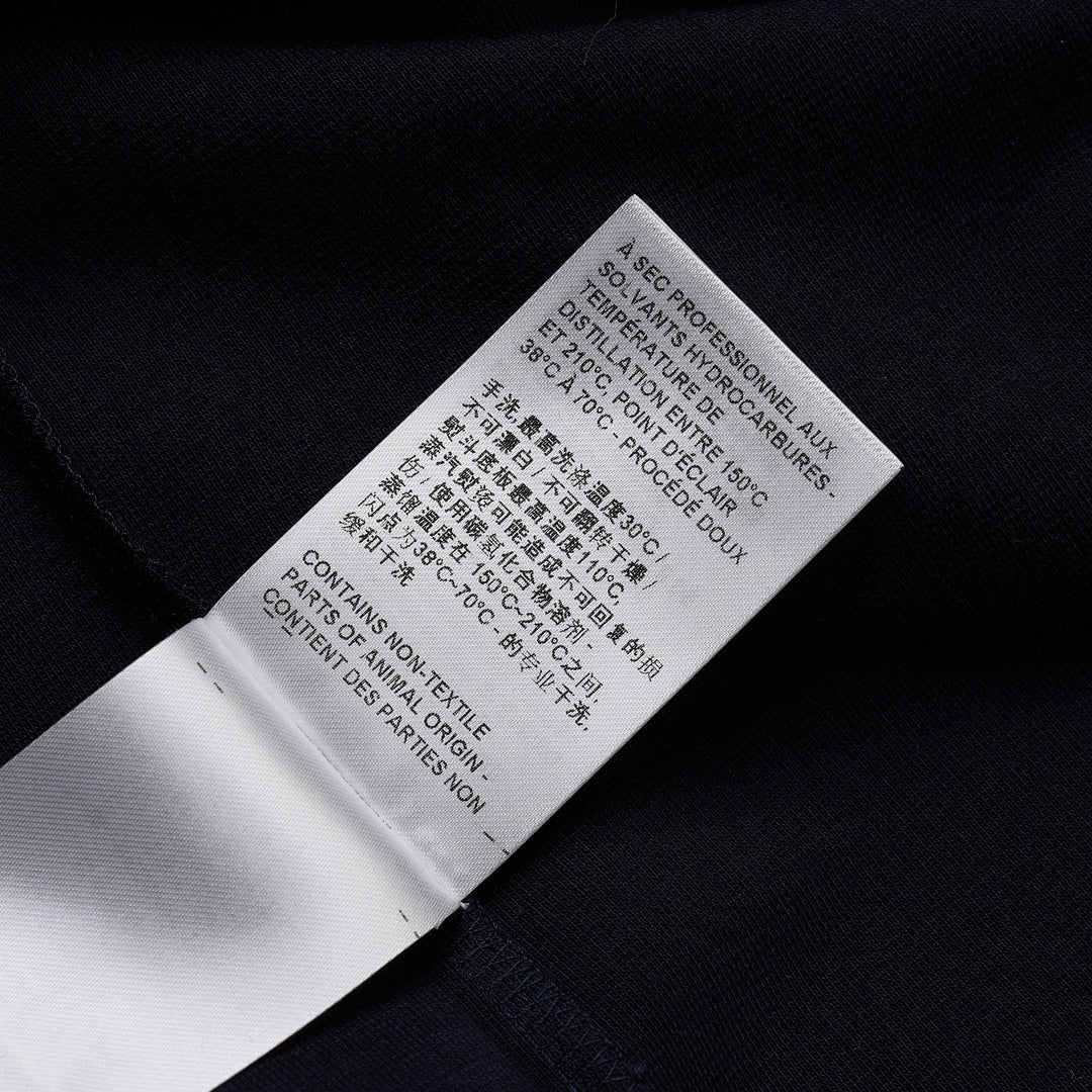 Thom Browne navy short sleeve polo with tonal 4-bar stripe on the sleeve, button placket, and woven brand label at the hem