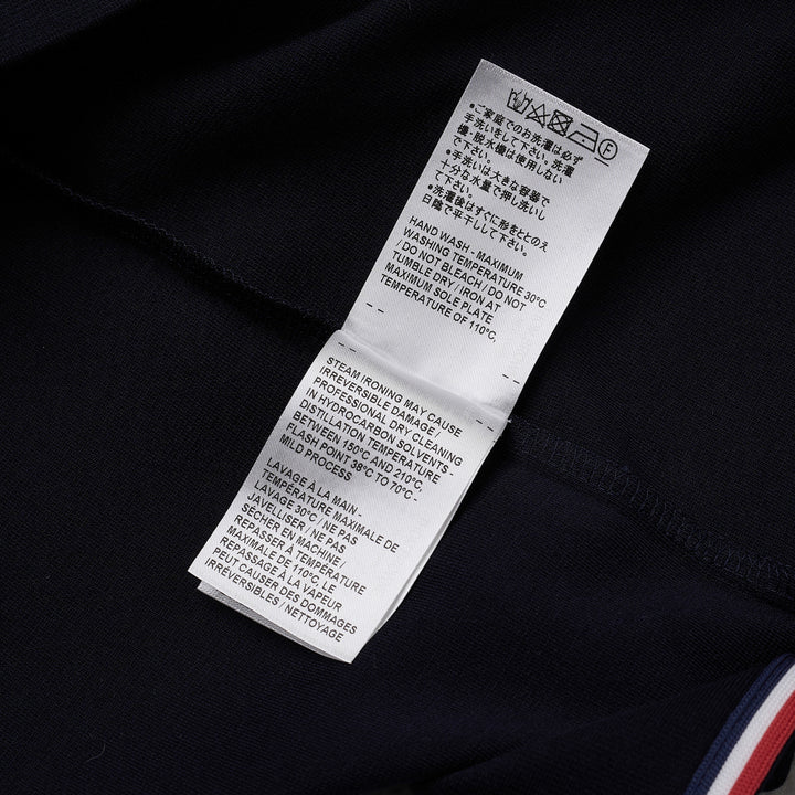 Thom Browne navy short sleeve polo with tonal 4-bar stripe on the sleeve, button placket, and woven brand label at the hem