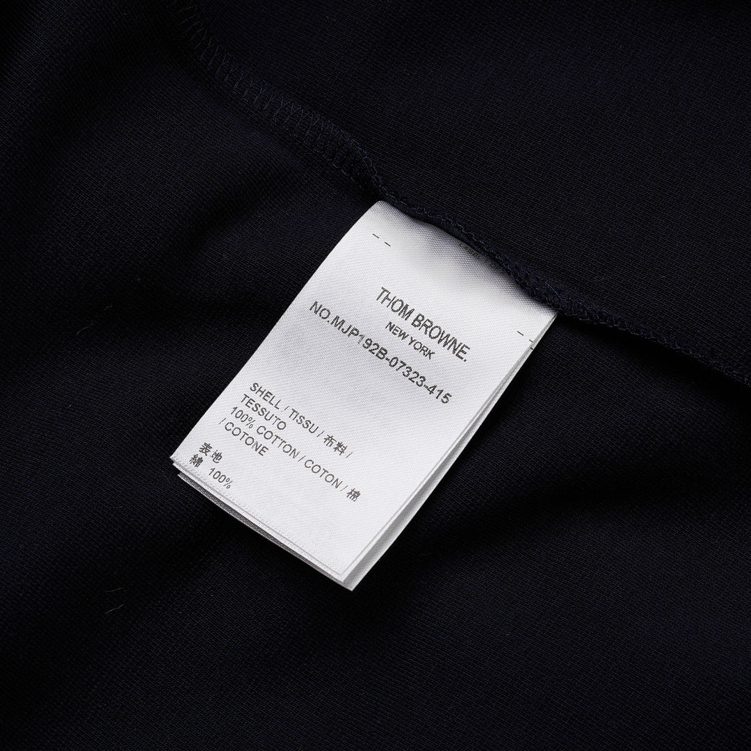 Thom Browne navy short sleeve polo with tonal 4-bar stripe on the sleeve, button placket, and woven brand label at the hem