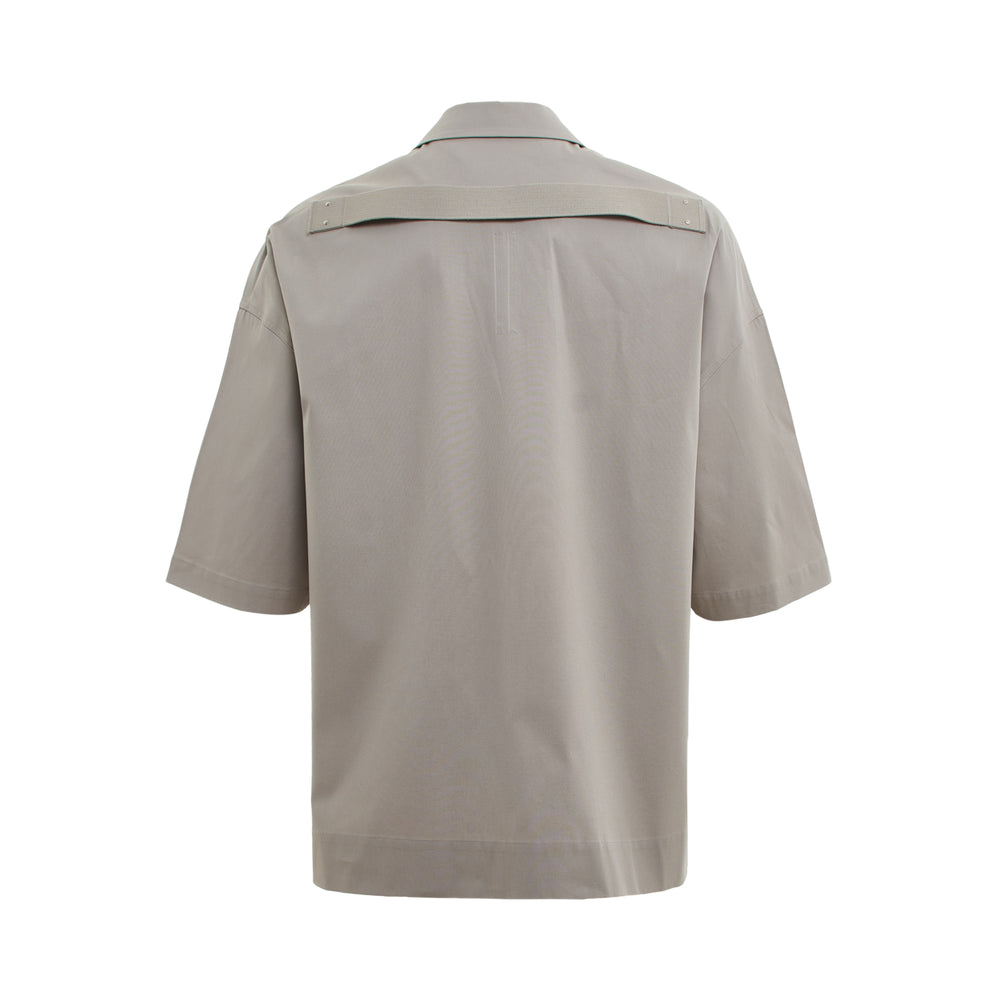 Rick Owens Magnum Tommy Short Sleeve Shirt in warm grey, featuring an oversized boxy fit, camp collar, concealed front placket, dual flap chest pockets, and topstitched panelled construction