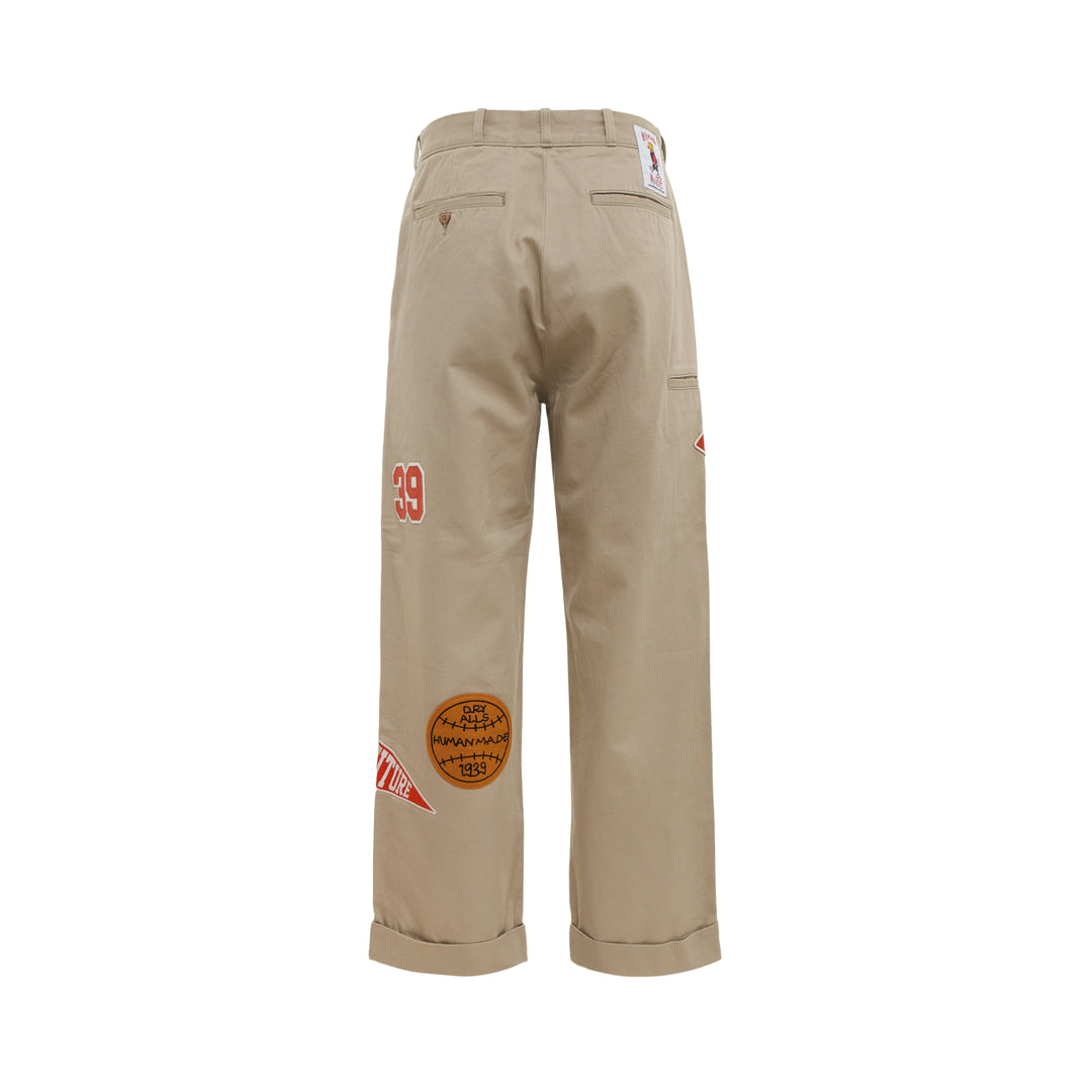 Human Made College Patch Pants in khaki with embroidered varsity patches and chenille H logo on straight-leg cuffed chinos