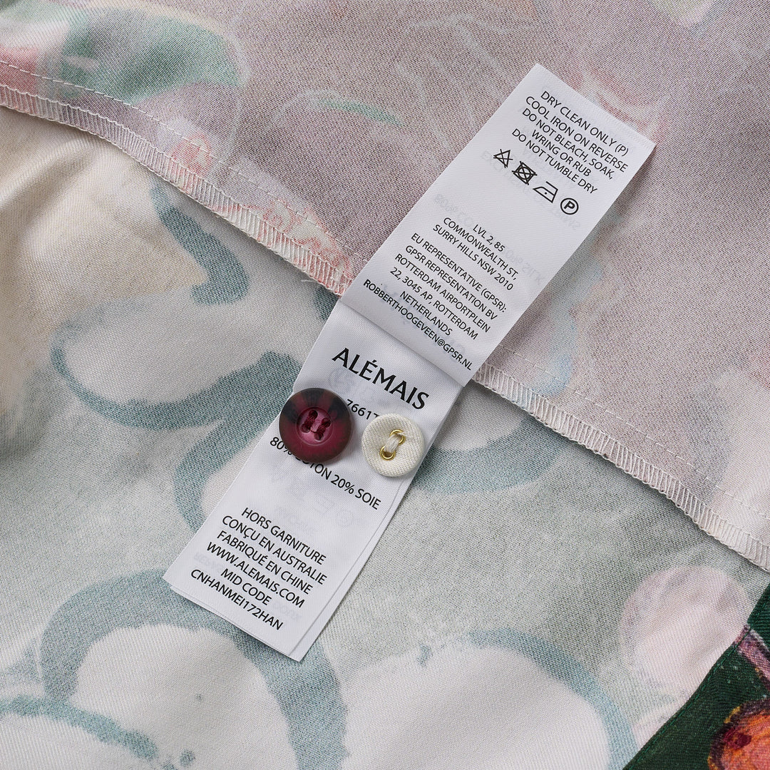Alemais Tangible Love short-sleeve shirt with patchwork hand-painted panels featuring crocodile, floral, and abstract motifs, oversized hem pockets, and contrast stripe trim on a white background