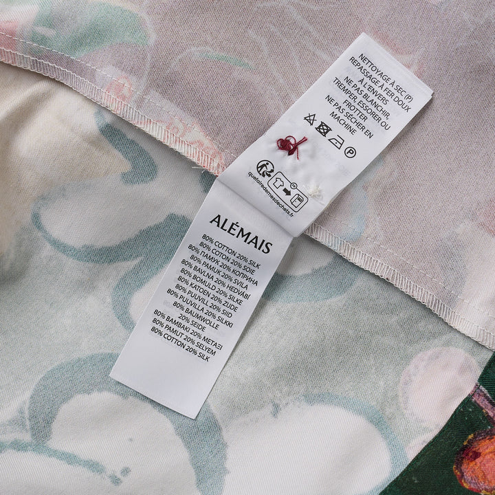 Alemais Tangible Love short-sleeve shirt with patchwork hand-painted panels featuring crocodile, floral, and abstract motifs, oversized hem pockets, and contrast stripe trim on a white background