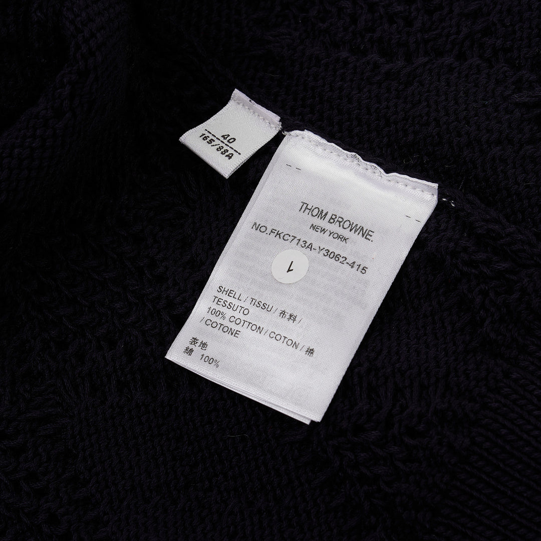Thom Browne navy pointelle-knit short sleeve V-neck cardigan with contrast ivory trim, four-bar stripe on the sleeve, and mother-of-pearl button fastening