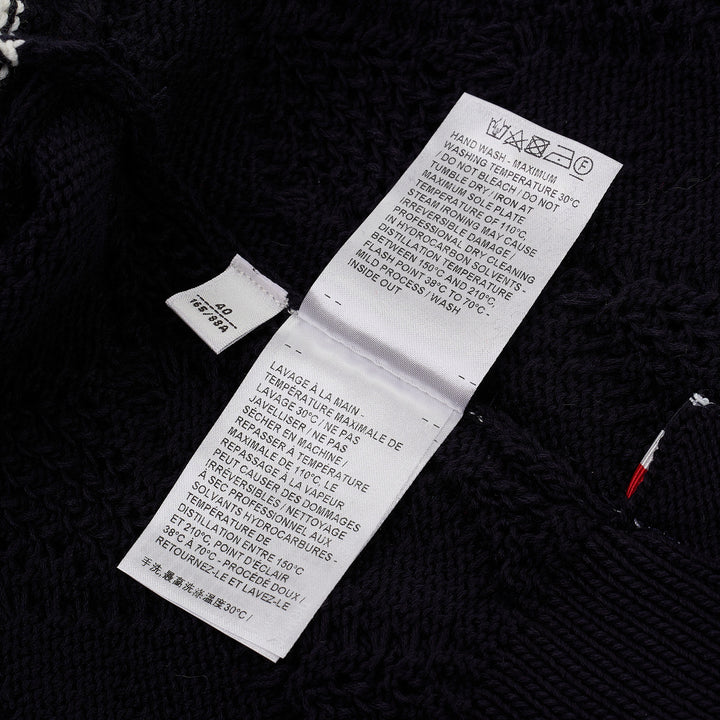Thom Browne navy pointelle-knit short sleeve V-neck cardigan with contrast ivory trim, four-bar stripe on the sleeve, and mother-of-pearl button fastening