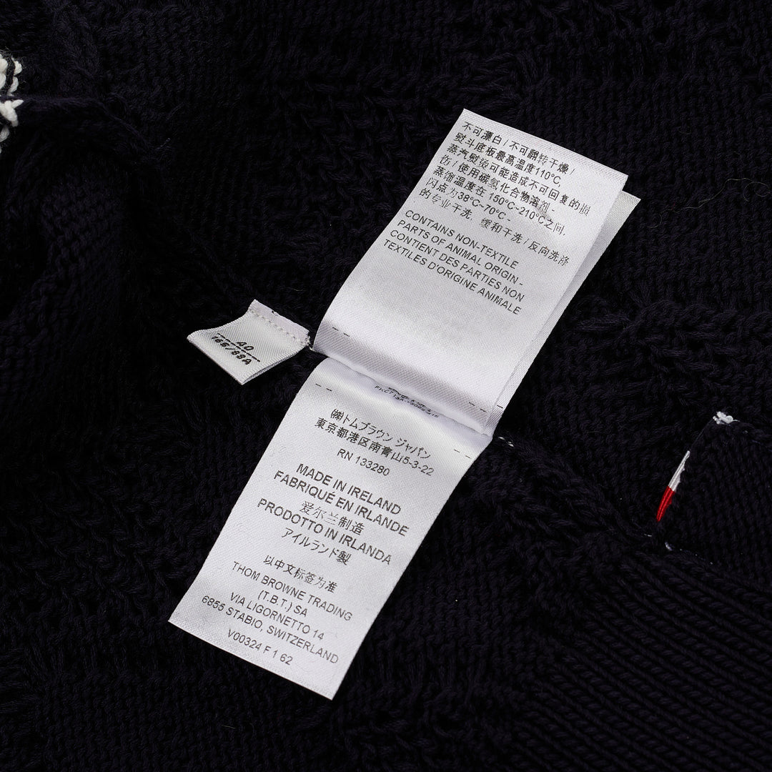 Thom Browne navy pointelle-knit short sleeve V-neck cardigan with contrast ivory trim, four-bar stripe on the sleeve, and mother-of-pearl button fastening