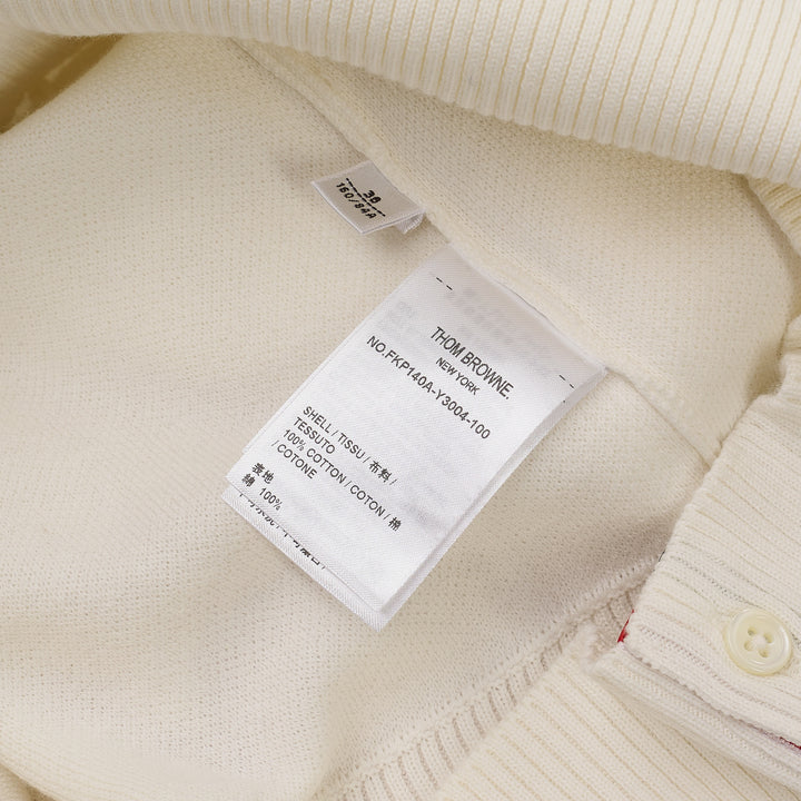 Thom Browne white short sleeve knit polo with red and white striped collar, signature red, white, and blue stripe on both sleeves, and four-button placket