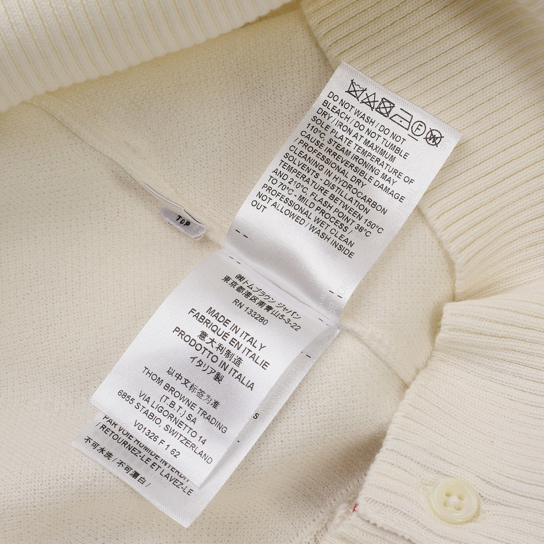Thom Browne white short sleeve knit polo with red and white striped collar, signature red, white, and blue stripe on both sleeves, and four-button placket