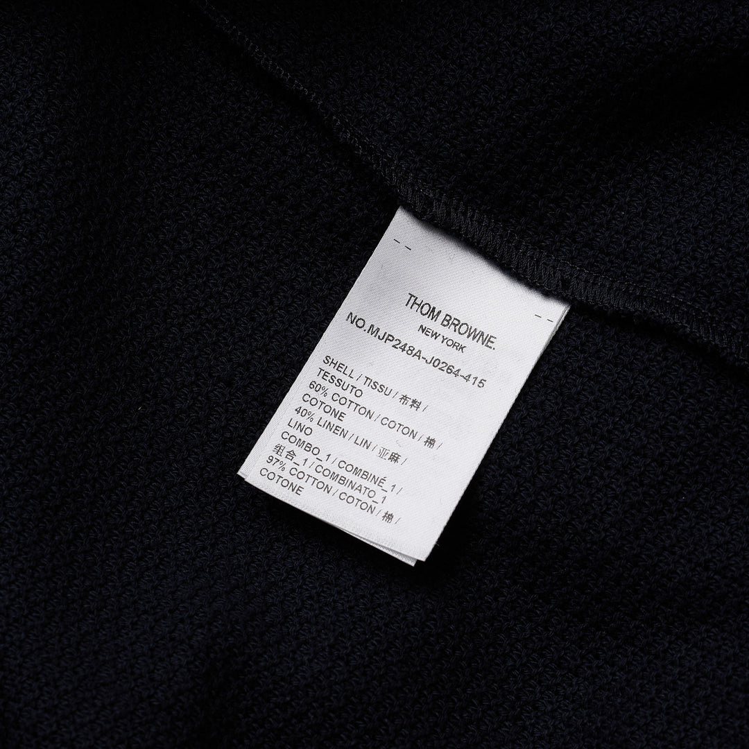 Thom Browne navy textured knit relaxed fit short sleeve polo with spread collar, five-button placket, chest pocket, and signature branding tab at the hem