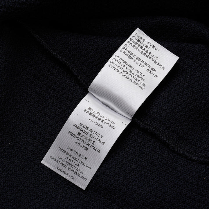 Thom Browne navy textured knit relaxed fit short sleeve polo with spread collar, five-button placket, chest pocket, and signature branding tab at the hem