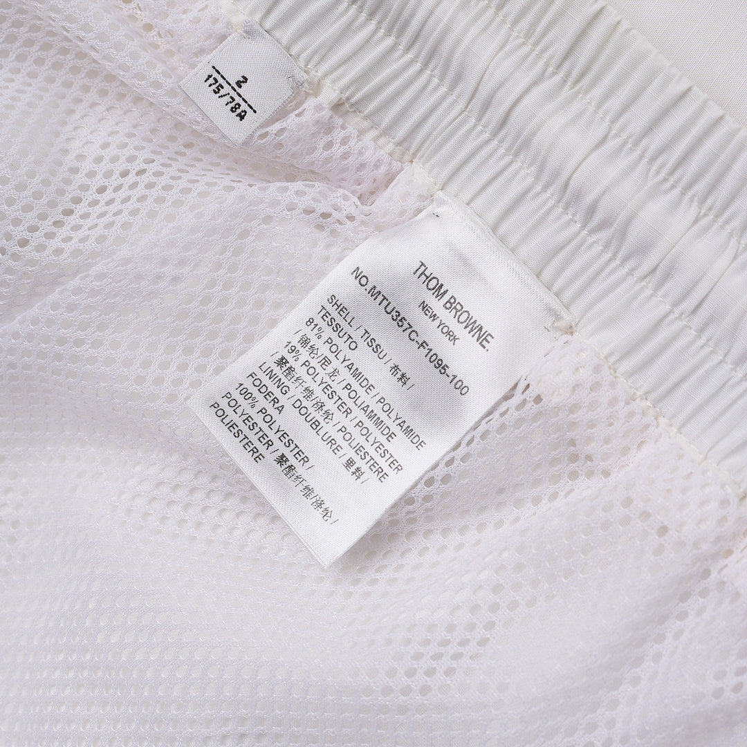 Thom Browne white drawcord waist track shorts with signature 4-bar navy stripe across the hem and elasticated waistband