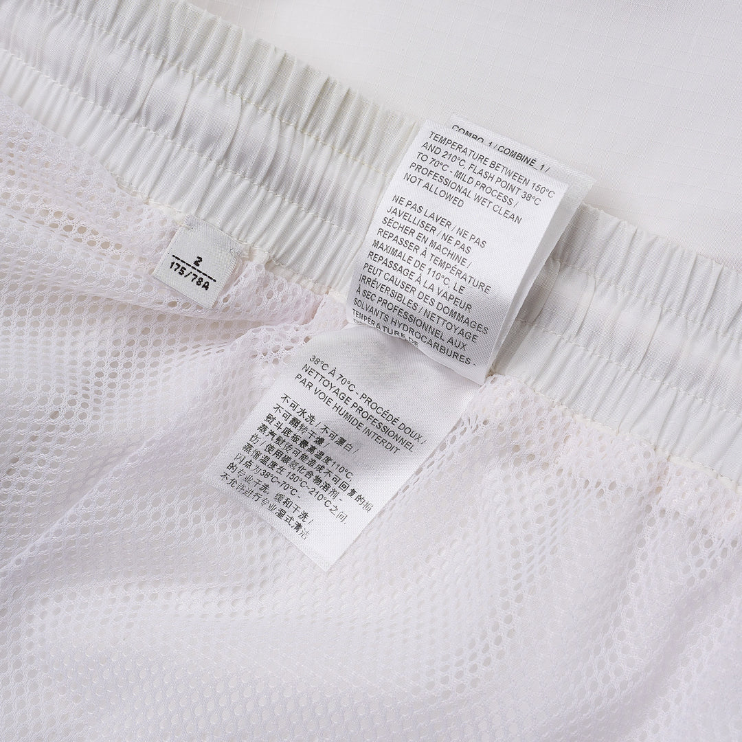 Thom Browne white drawcord waist track shorts with signature 4-bar navy stripe across the hem and elasticated waistband