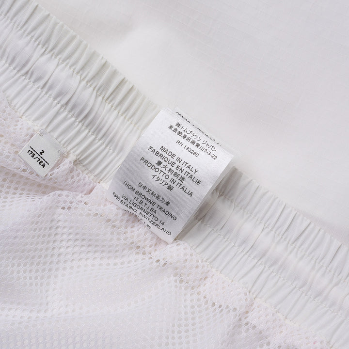 Thom Browne white drawcord waist track shorts with signature 4-bar navy stripe across the hem and elasticated waistband