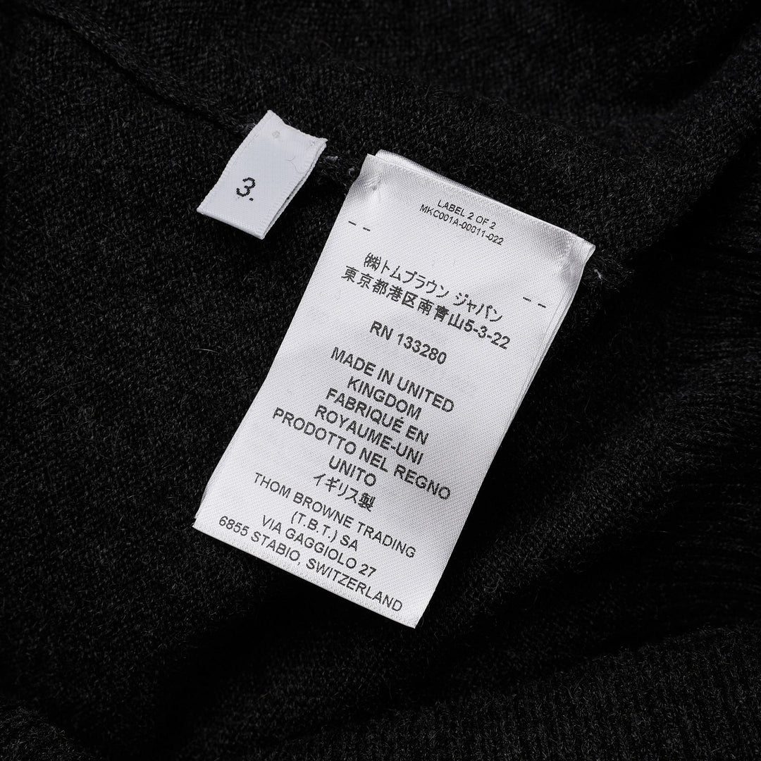 Thom Browne Classic V-Neck Cardigan in dark charcoal grey with signature four-bar white and black stripe on the sleeve, button-front closure, and ribbed hem