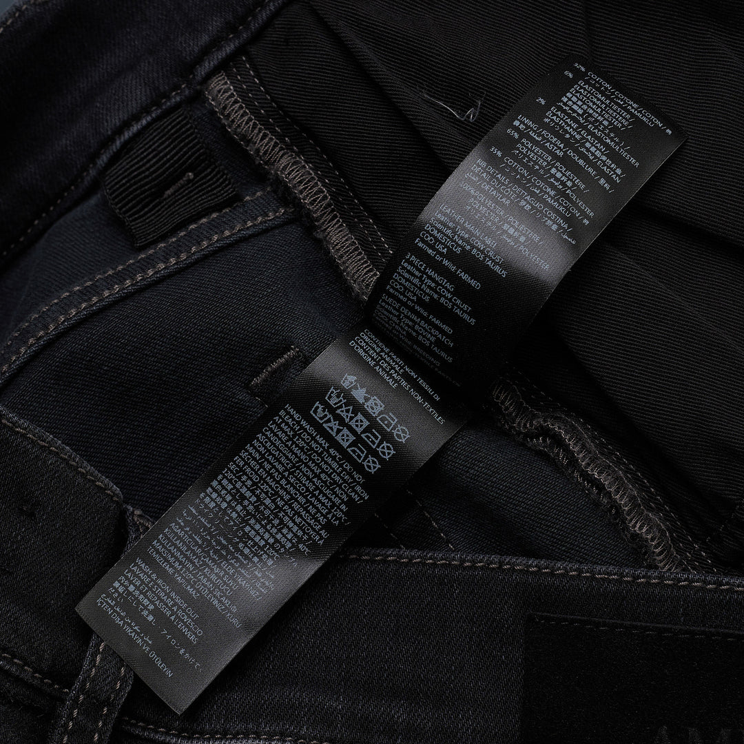 Amiri Camo MX1 Jeans in washed black denim with distressed knee rips and camouflage underlay patches, skinny fit, front view
