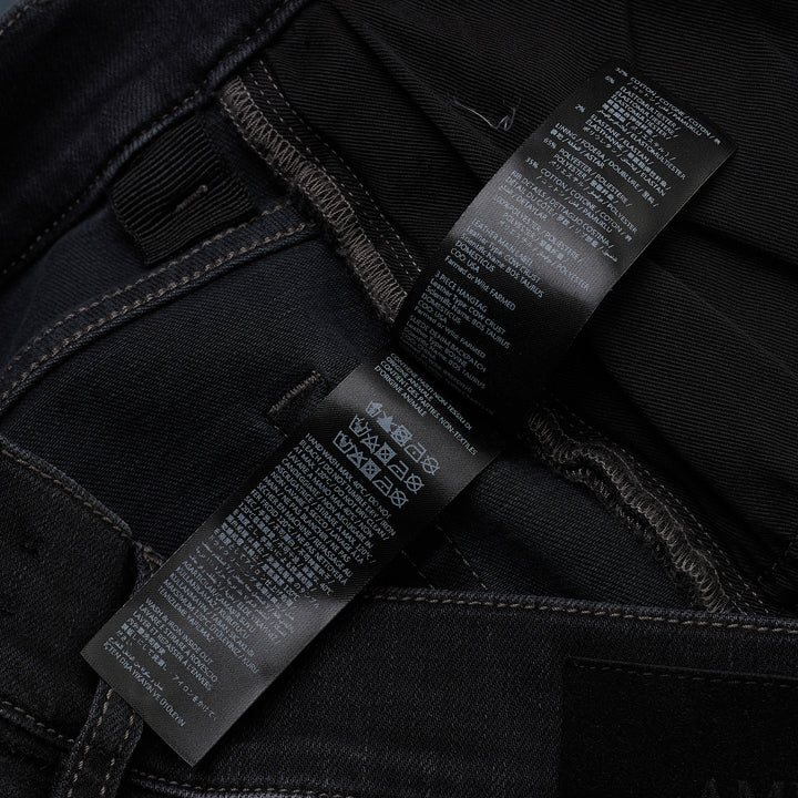 Amiri Camo MX1 Jeans in washed black denim with distressed knee rips and camouflage underlay patches, skinny fit, front view