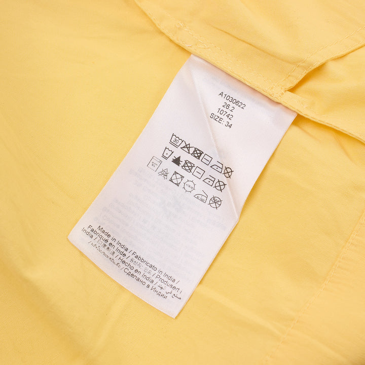 Ganni yellow stretch cotton smocked mini dress with puff sleeves and drop-waist bubble skirt, shot against a white background