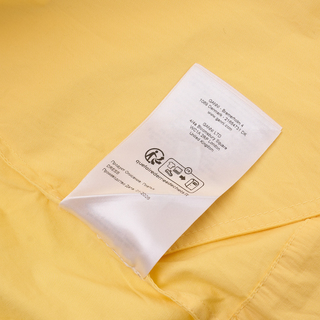 Ganni yellow stretch cotton smocked mini dress with puff sleeves and drop-waist bubble skirt, shot against a white background