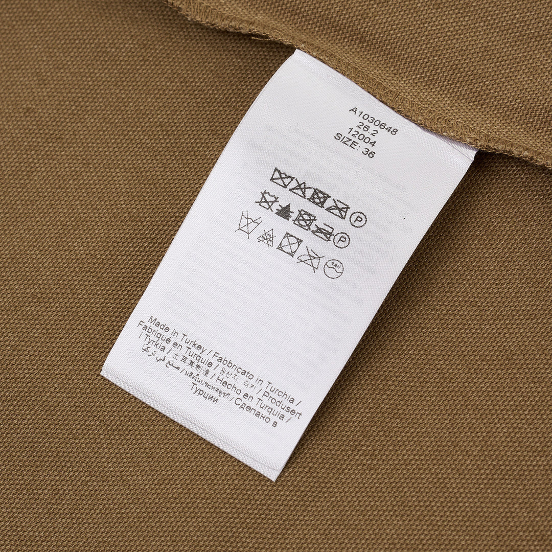 Ganni Workwear Canvas Boxy Mini Dress in khaki, back view, featuring branded lace hem trim and dark floral appliqué detail