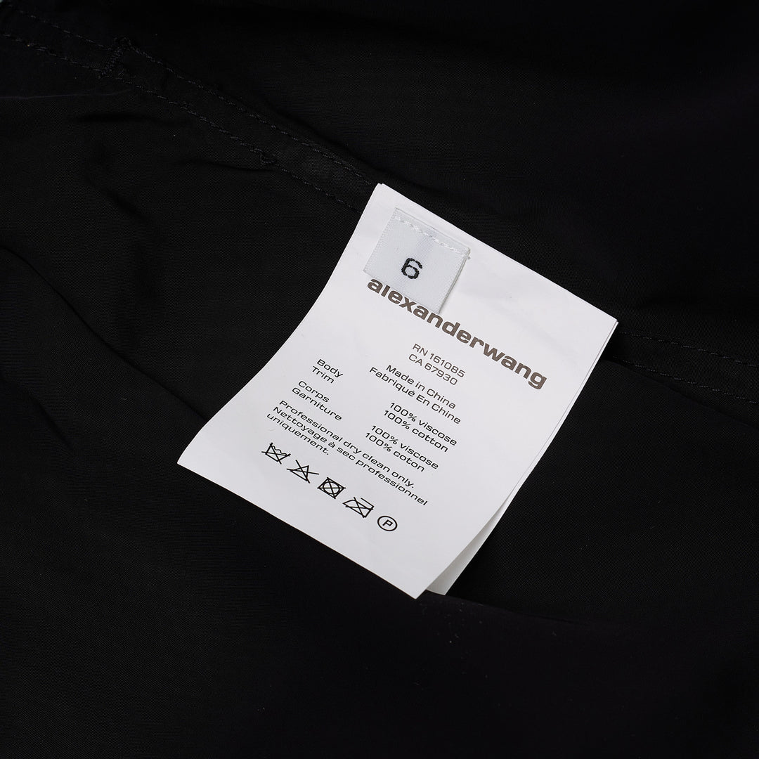 Alexander Wang mid-rise shorts with acid-wash denim waistband and pleated black fabric body, featuring silver snap button and contrast orange topstitching