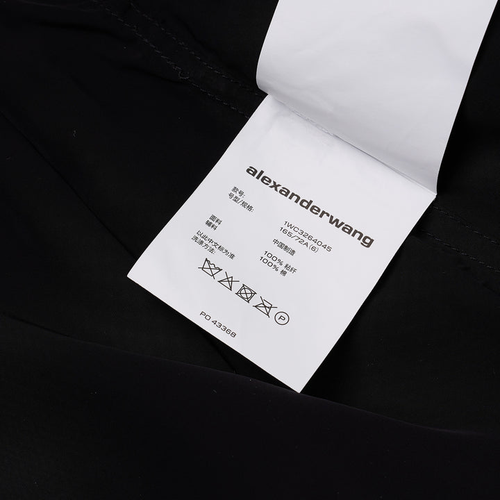 Alexander Wang mid-rise shorts with acid-wash denim waistband and pleated black fabric body, featuring silver snap button and contrast orange topstitching