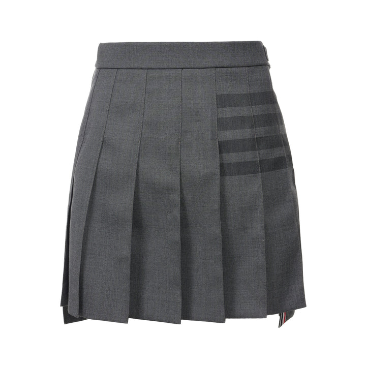Thom Browne grey pleated mini skirt with tonal 4-bar stripe on one panel and red, white, and blue grosgrain tab at hem