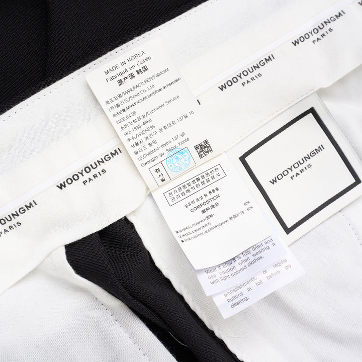 Wooyoungmi black pleated high-rise trousers with double front pleats and side metal buckle adjuster, displayed flat on white background - view 4
