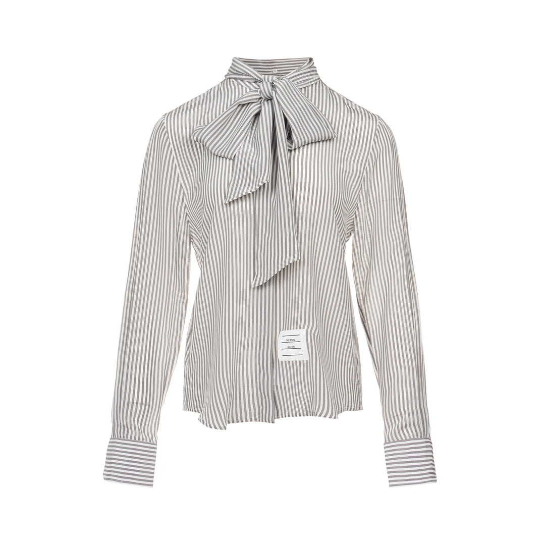 Thom Browne grey and white vertical stripe long sleeve blouse with detachable pussy-bow collar, contrast horizontal-stripe cuffs, and signature woven label patch at the hip