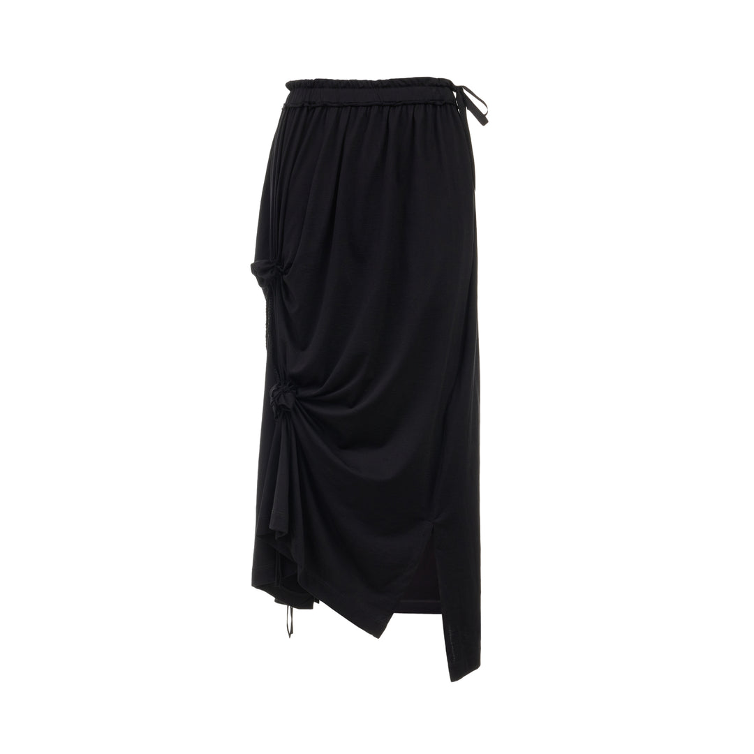 Y's Lace-Up String Flare Skirt in black, featuring elasticated waistband with ribbon tie, ruched drawstring knots, fluid drape, and asymmetric midi hem