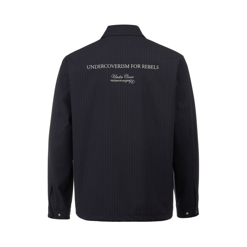 Undercover navy pinstripe snap-button coach jacket with embroidered logo patch, pointed collar, and ribbed cuffs, displayed on a flat white background - view 2