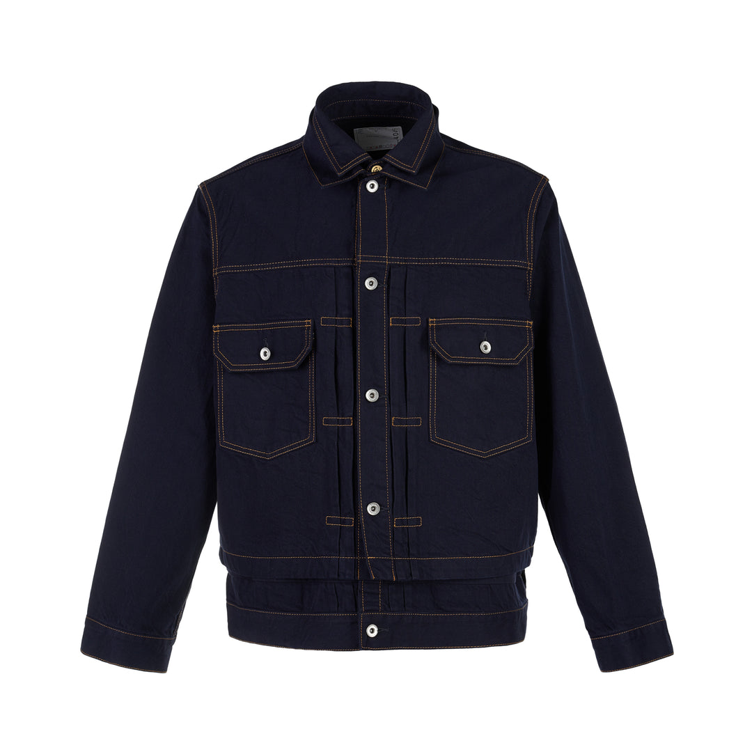 sacai indigo denim trucker jacket with contrast topstitching, pleated front panels, button-flap chest pockets and a layered hem, shown from the front