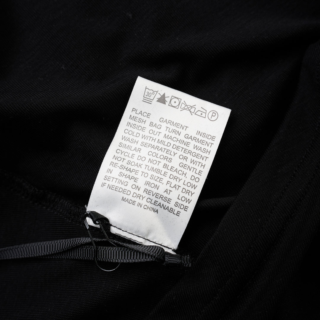 Black short-sleeve crew neck jersey tee with gathered side draping and an asymmetric hem, shown flat against a white background - view 3