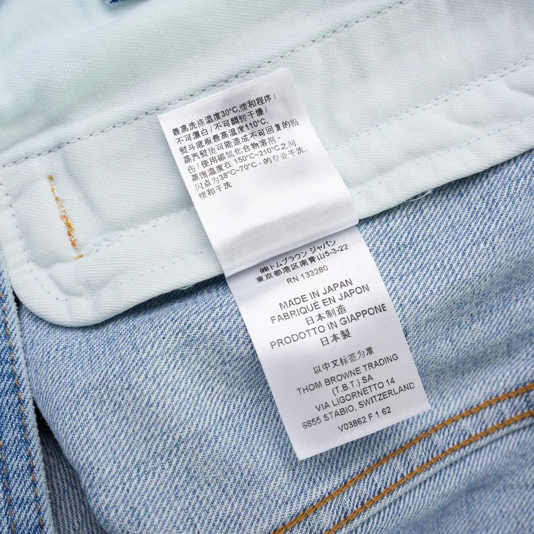 Thom Browne Backstrap Utility Jacket in light-wash denim with twin chest flap pockets and brass buttons, shown from the front - view 5