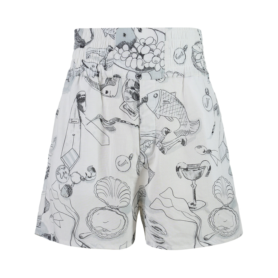 Jacquemus Le Boxer shorts in white with a black and grey illustrated print of shells, fish, grapes and champagne coupes, shown with a smocked high waistband