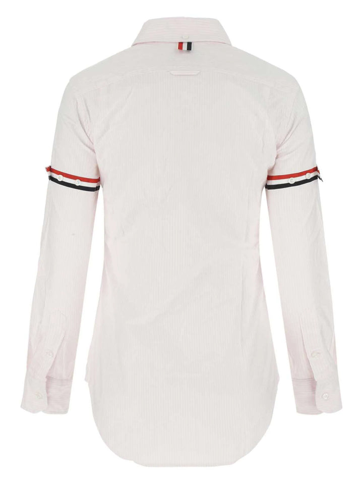 Thom Browne classic long sleeve light blue pinstripe shirt with tricolor grosgrain ribbon armbands, front view on white background