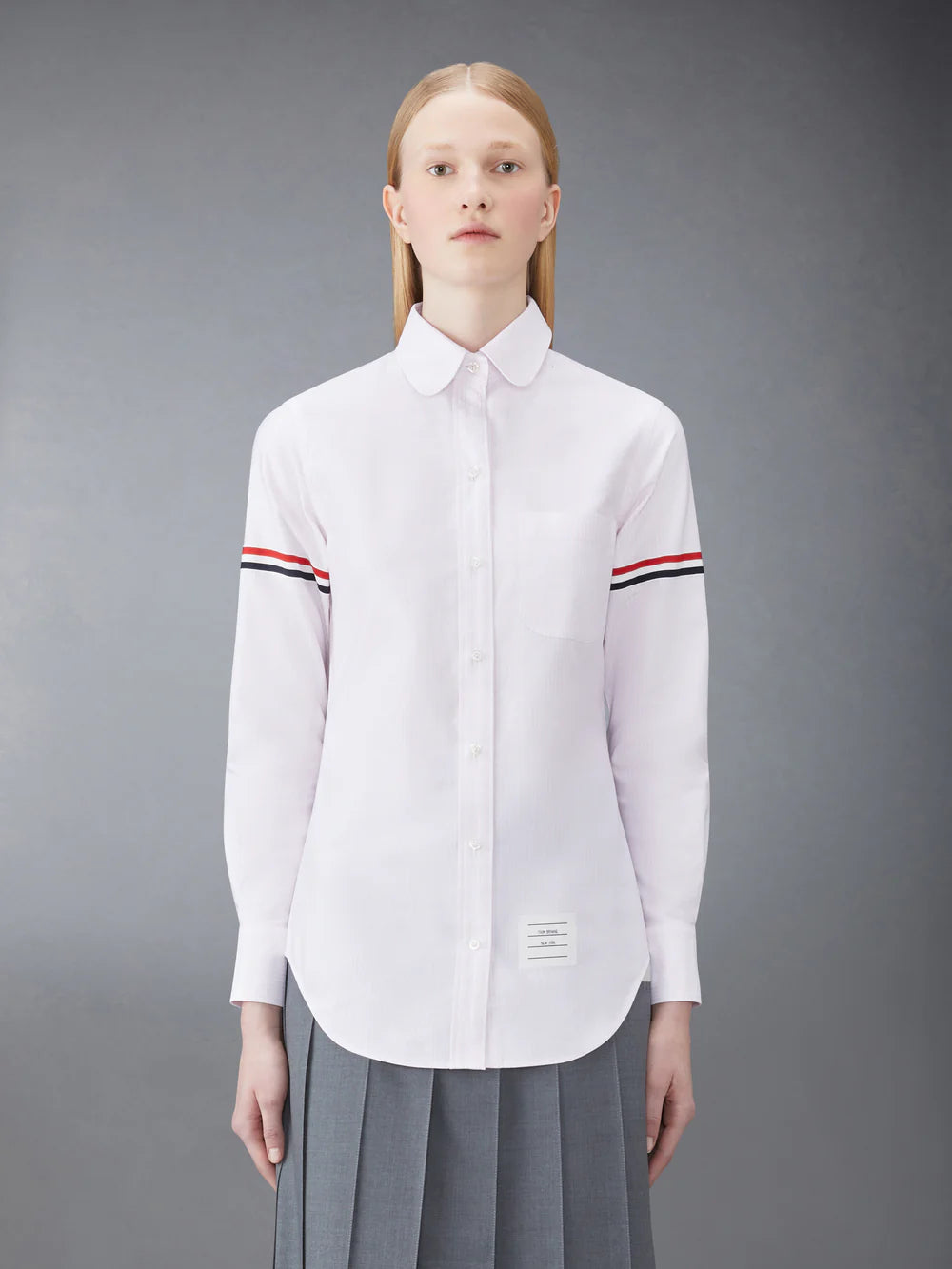 Thom Browne classic long sleeve light blue pinstripe shirt with tricolor grosgrain ribbon armbands, front view on white background