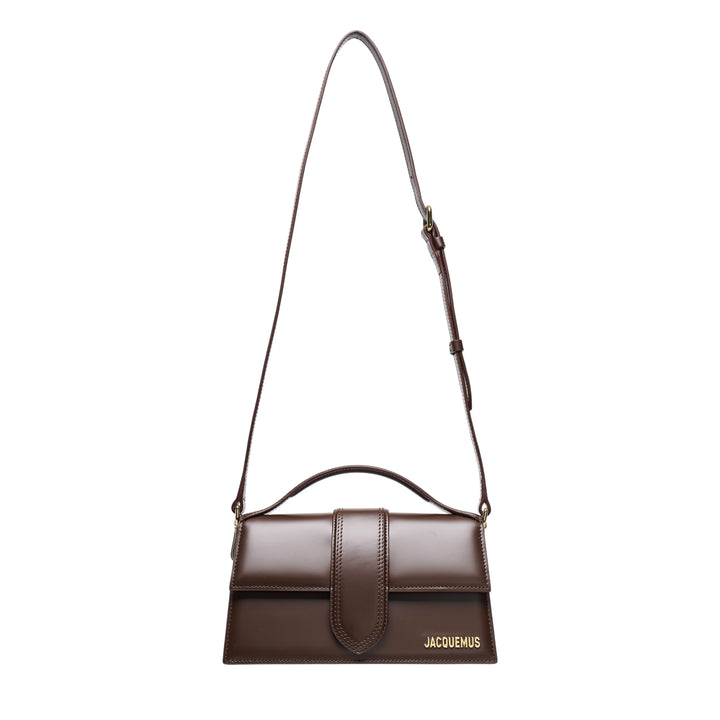 Jacquemus Le Grand Bambino smooth dark brown leather shoulder bag with adjustable crossbody strap, curved top handle, central flap tab closure, and gold-tone hardware and branding