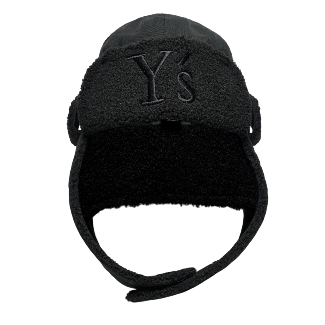 Y's all-black wool trapper hat with sherpa fleece lining, fold-down ear flaps with chin strap, and tonal embroidered Y's logo on the front panel, photographed from the front on a white background.