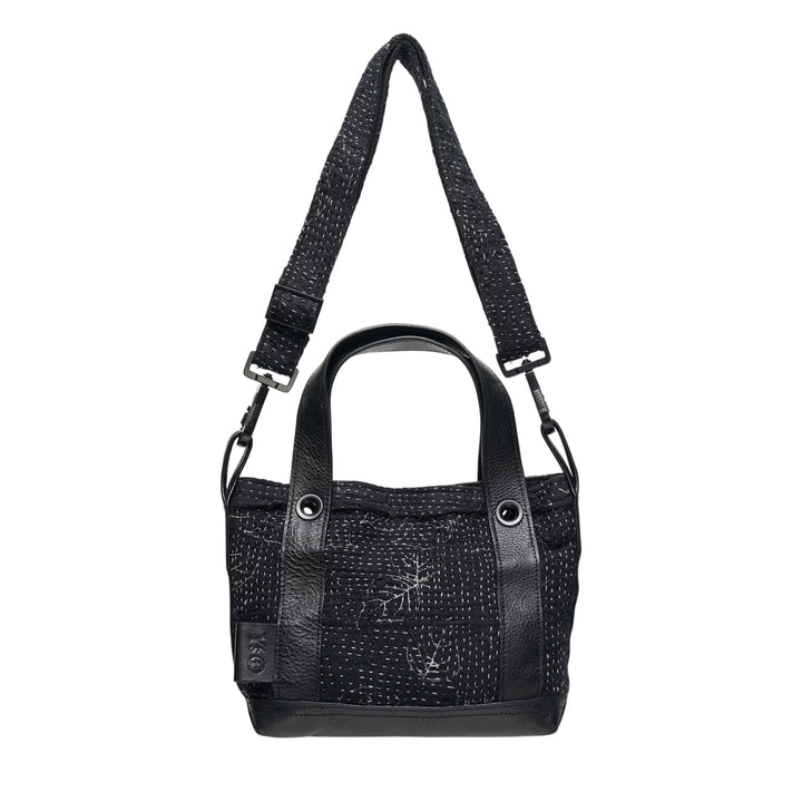 Y's x FAF 008 black kantha-stitched tote bag with pebbled leather trim, dual short handles, and a wide adjustable crossbody strap with gunmetal hardware