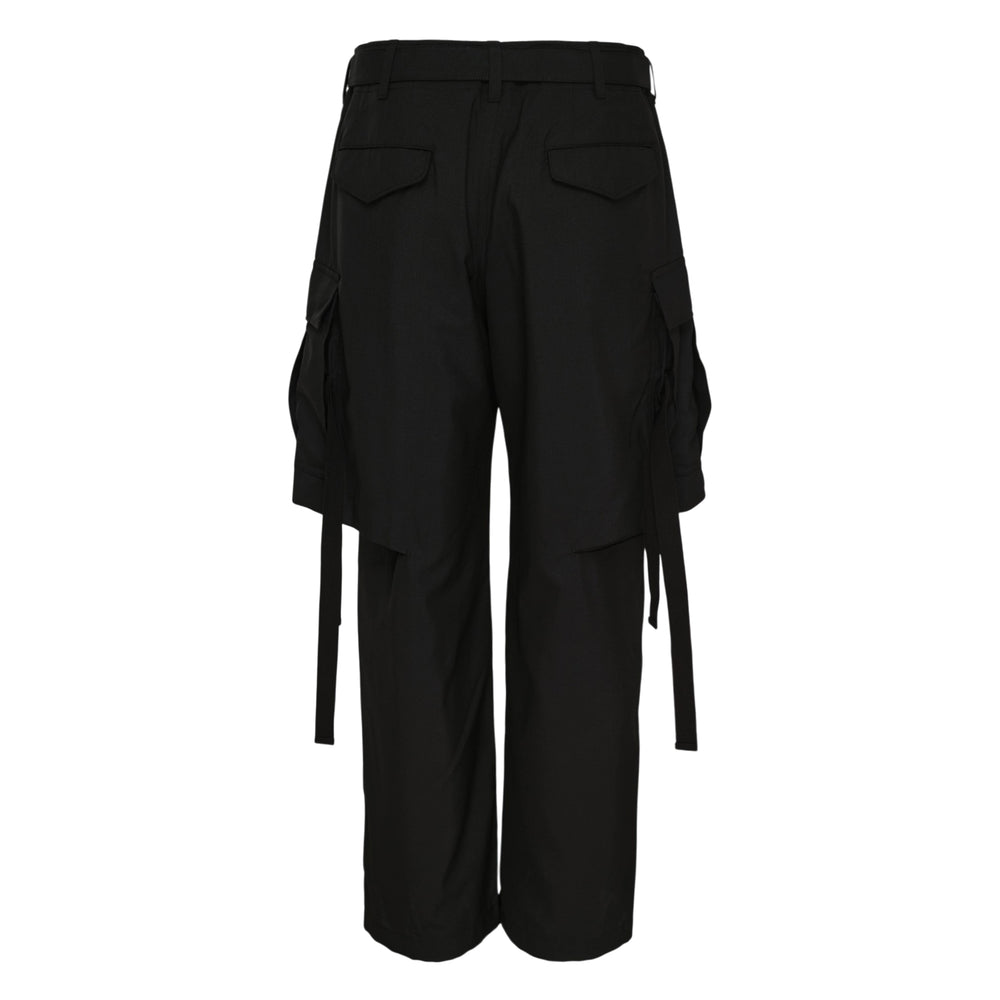 sacai black suiting cargo pants with wide-leg silhouette, deep front pleats, oversized cargo pockets, webbing strap details, and an integrated buckle belt at the waistband