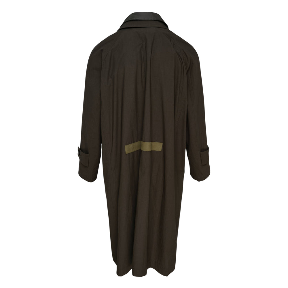 sacai Cotton Typewriter Coat in khaki with olive webbing buckle straps, leather-trimmed chest pockets, and a contrast knit collar accent — front view