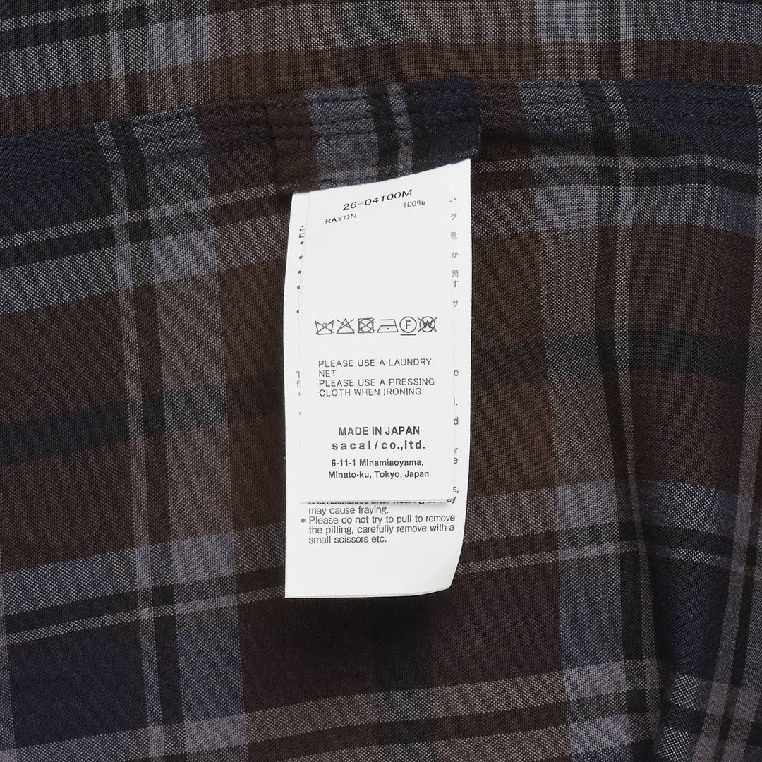 sacai plaid flannel long sleeve shirt in brown, navy, and grey check with deconstructed layered collar, dual chest pockets, and mother-of-pearl buttons, displayed flat on white background - view 3