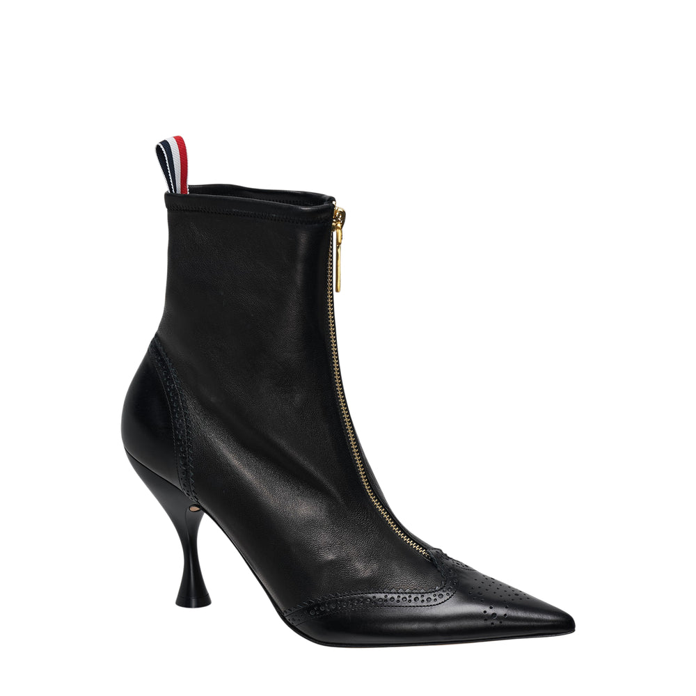 Thom Browne black stretch leather wingtip ankle bootie with brogue perforations, sculptural 90mm heel, gold back zip, and tricolour loop pull