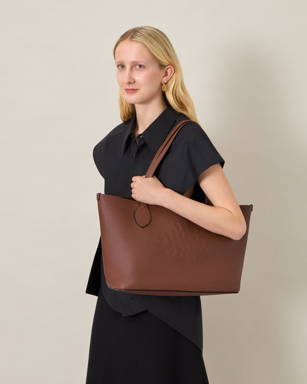 Mulberry Tree Tote in black heavy grain leather, featuring tonal cutwork Mulberry tree motif on the front panel and twin flat shoulder straps with teardrop finials