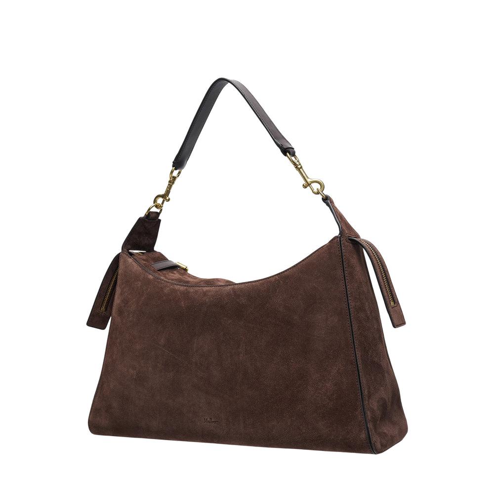 Mulberry Roxanne medium shoulder bag in chocolate brown suede with dual front patch pockets, gold-tone buckle hardware, and a single leather shoulder strap on a white background
