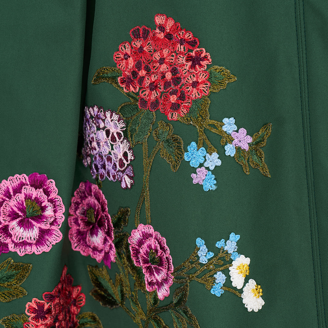 Carolina Herrera dark green A-line midi skirt with vibrant multicolour floral embroidery along the hem, featuring red, pink, and purple blooms with green leafy stems on both front panels