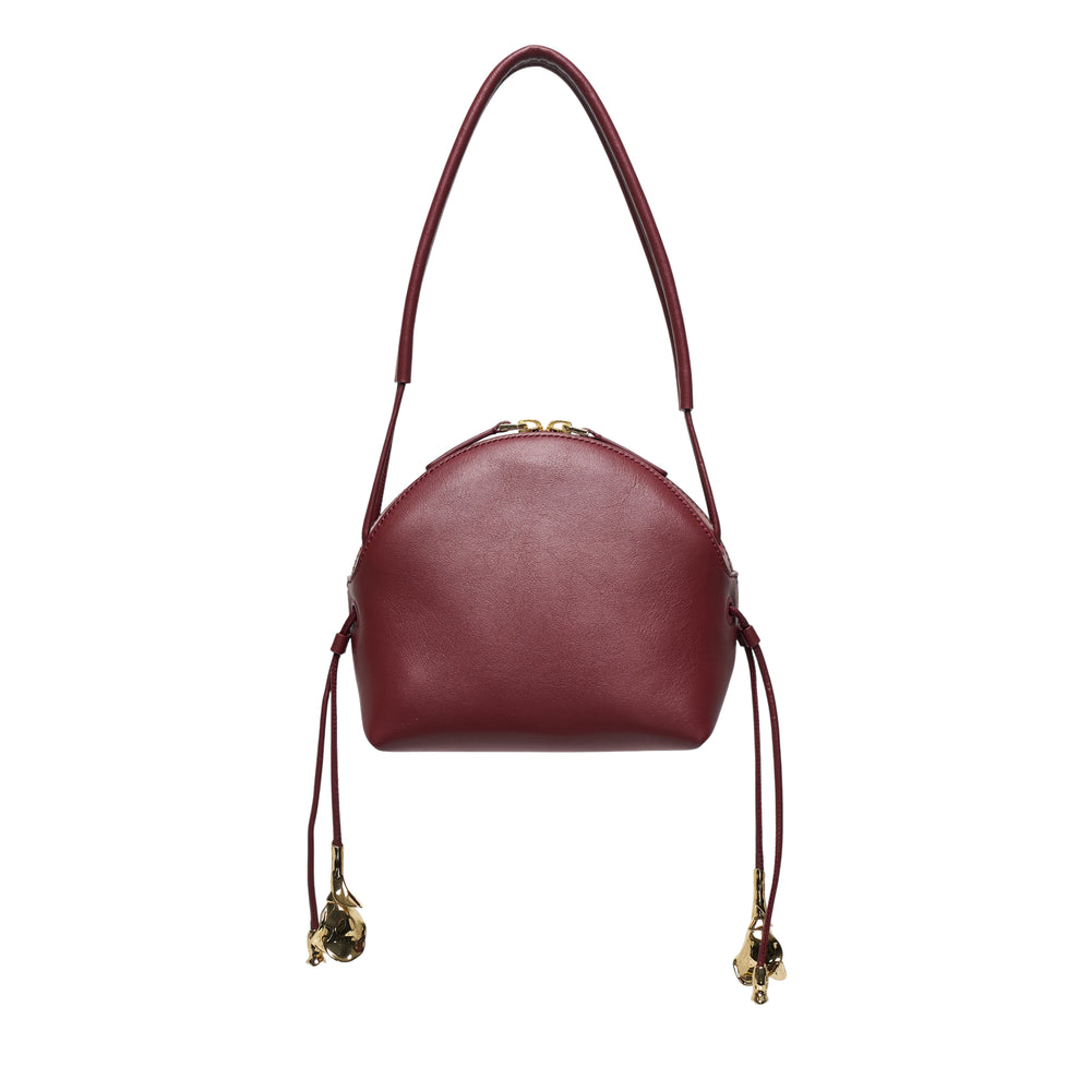 Erdem Flora Day Bag in deep burgundy smooth leather with a domed silhouette, top zip closure, slim shoulder strap, and sculptural gold-tone floral tassel charms on drawstring side gathers