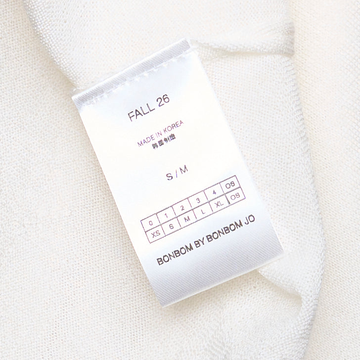 Back view of Bonbom Shoulder Tuck Sleeveless Top in off-white, showing tuck detailing at the shoulders, relaxed boxy silhouette, and woven Bonbom label at the hem